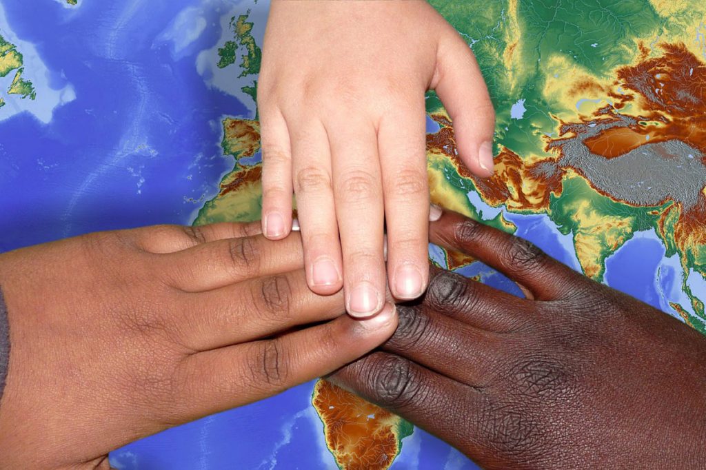 Hände unterschiedlicher Hautfarbe auf Weltkarte